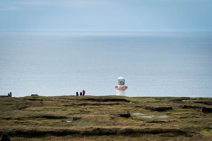 People standing at the lighthouse on Arranmore Island in Donegal