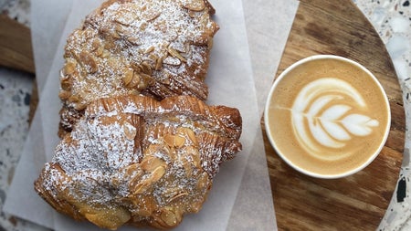 Freshly baked almond pastries served with a speciality coffee featuring latte art