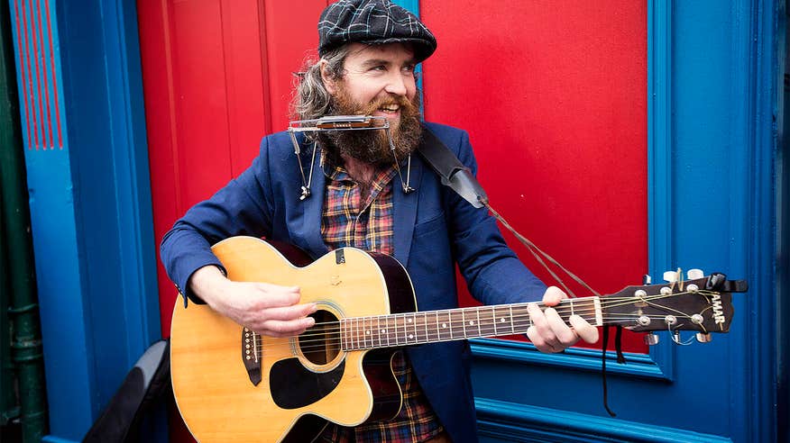 Man playing the guitar and the harmonica.