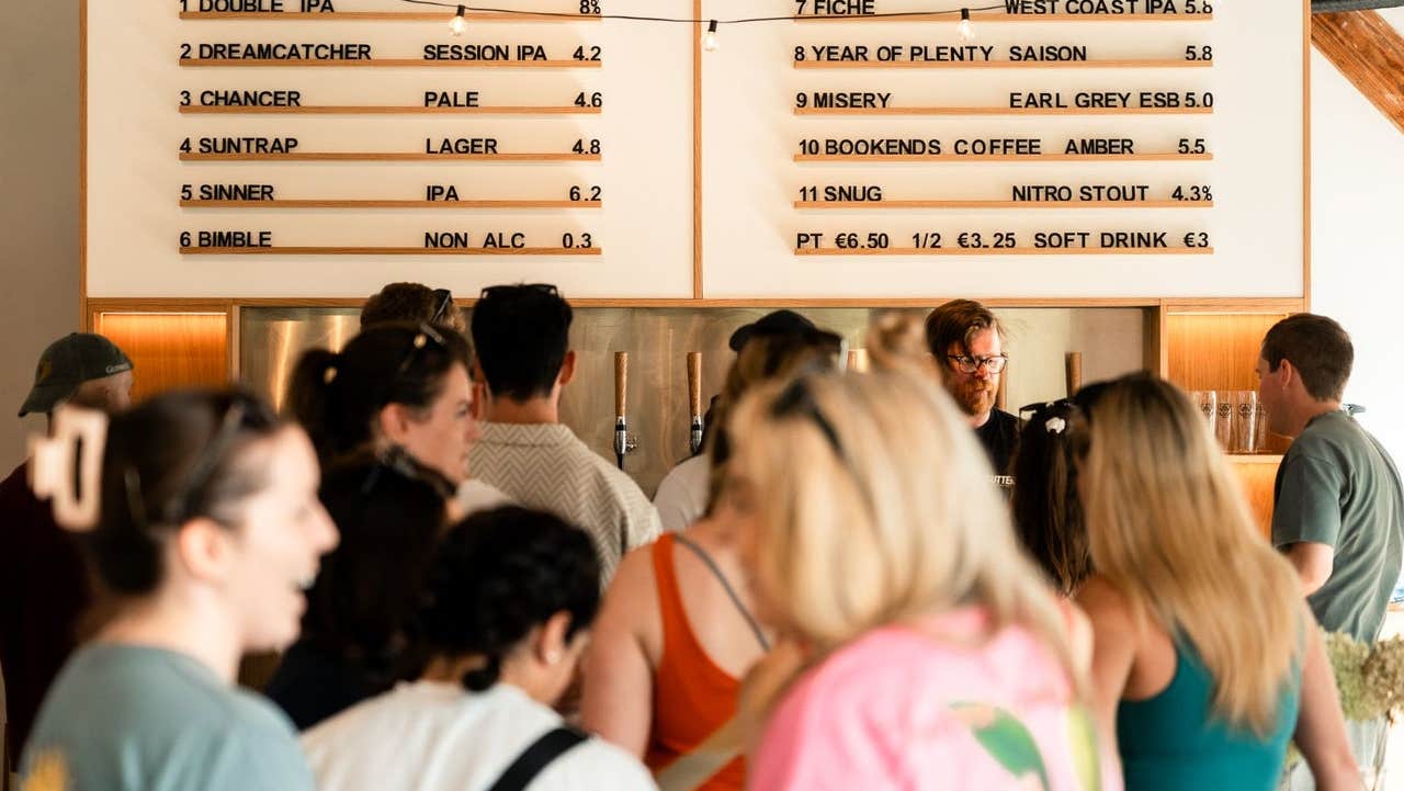 People standing under a drinks menu