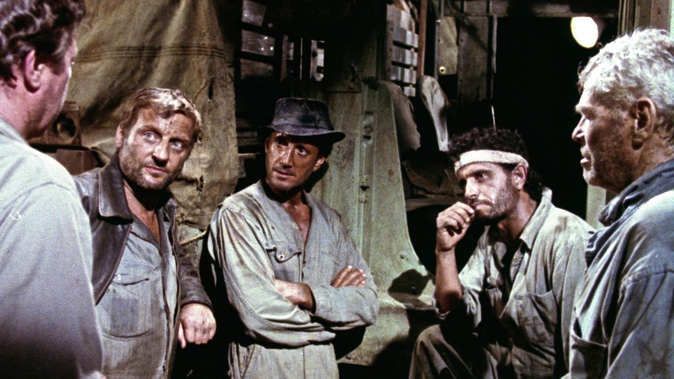 Five grimy men are having a discussion.