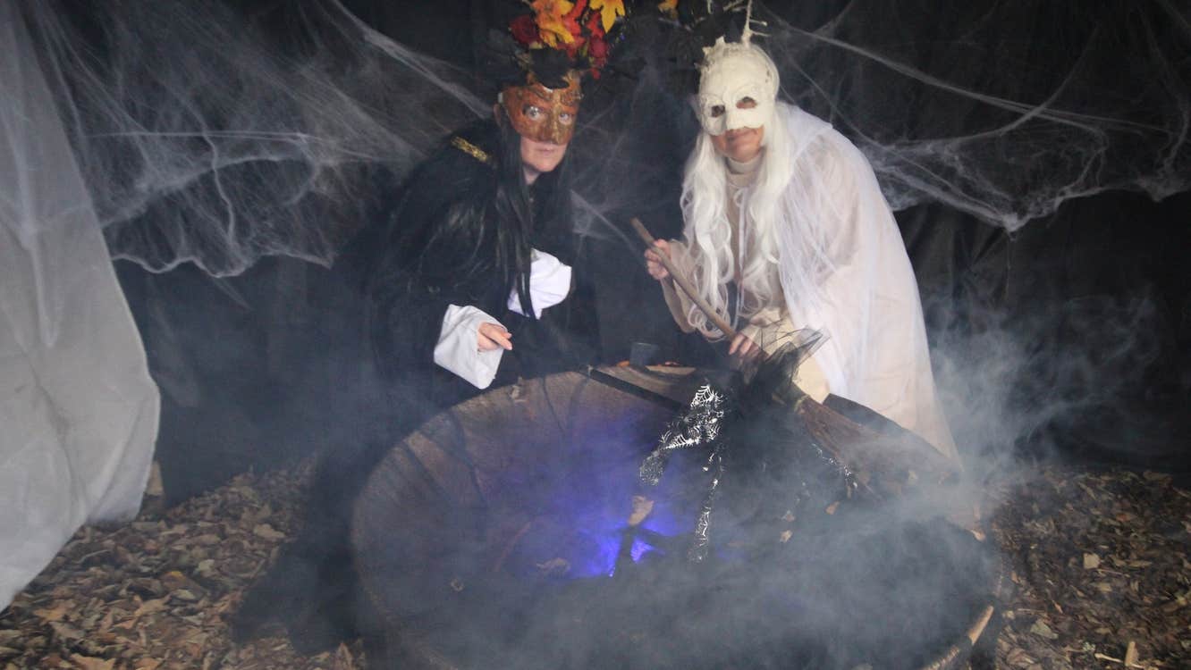 two people, one in white and one in black over a cauldron mixing it up