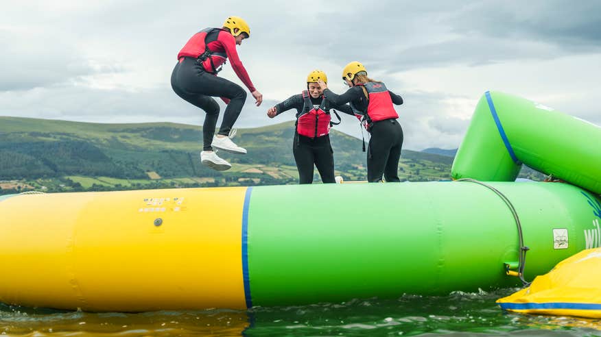 Three people bouncing on a water trampoline at Carlingford Adventure Centre in County Louth.