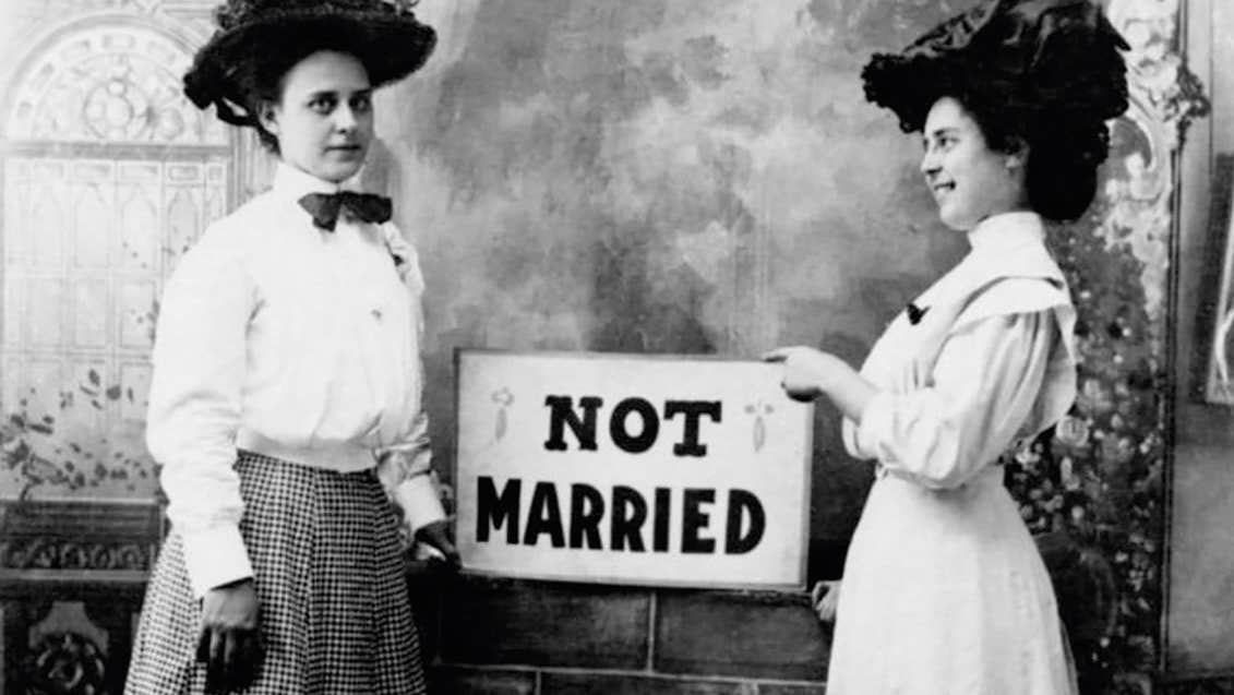 Two young women holding a sign that says 'Not Married'