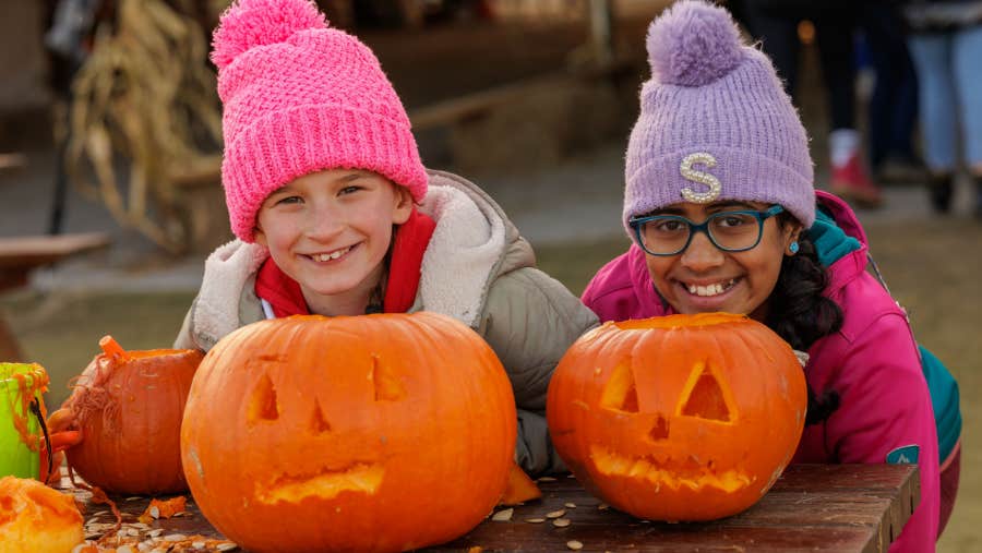 Two children beam with pride beside their freshly carved pumpkins at Nore Valley Park's Pumpkin Patch, a fun family activity included in every visit.