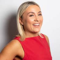 Enya Martin, a smiling woman in a red dress against a plain, light background.