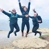 Overland Ireland Tours with women jumping near cliffs overlooking the sea