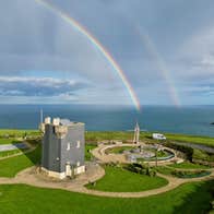 A signal tower beside the coast with a double rainbow in the sky