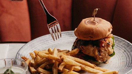 A gourmet style burger with fries on the side and a cocktail