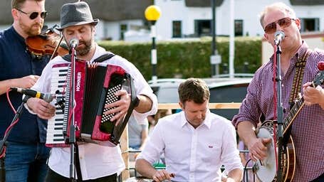 Dunmore East Bluegrass Festival, 4 musicians performing outdoors in a town.