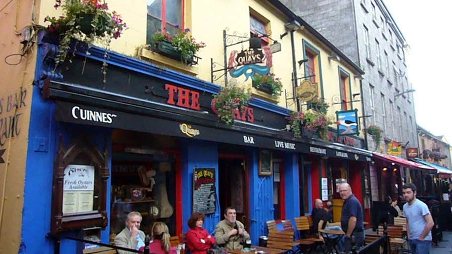 Exterior of The Quays pub Galway with people seated outside