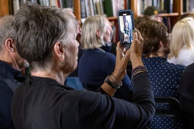 A woman holding a mobile phone up so she can record a traditional music session