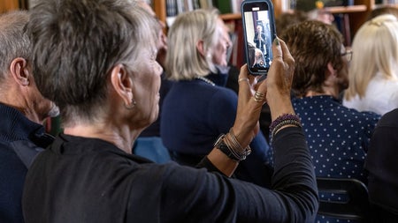 A woman holding a mobile phone up so she can record a traditional music session