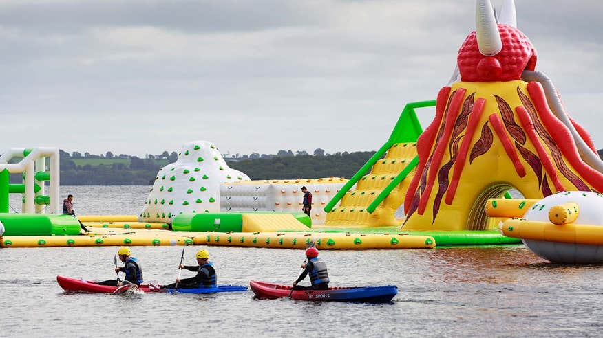 Three kayakers in the water beside inflatable toys in Athlone