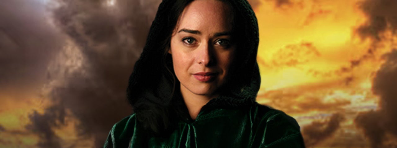 A woman is looking intently ahead in dark hooded cloak against dark, orange stormy sky.