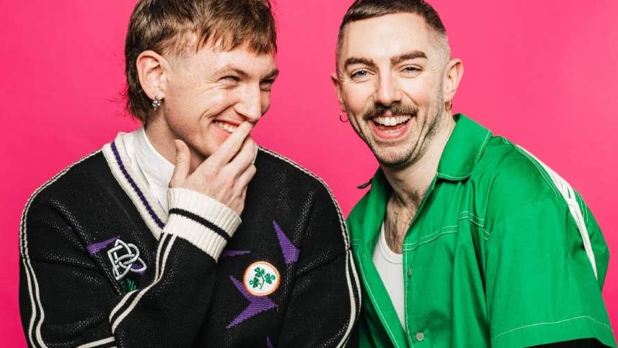 2 laughing men against bright pink background.