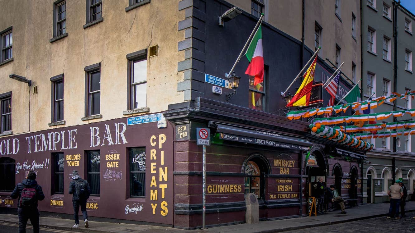 Exterior of a bar and restaurant on a corner in Temple Bar with flags outdoor decorations and traditional pub signage