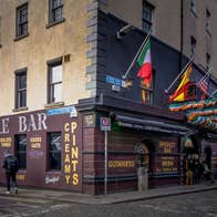 Exterior of a bar and restaurant on a corner in Temple Bar with flags outdoor decorations and traditional pub signage