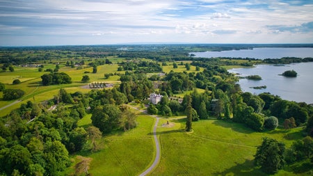 An aerial view of a large country estate with a period house in the distance