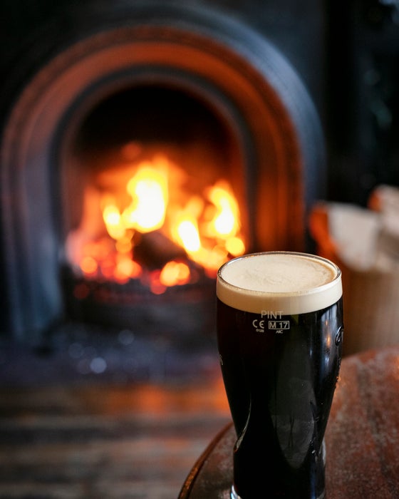 A pint in front of a fireplace.
