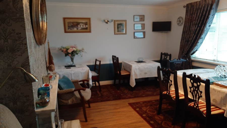 Dining room with white table clothes on table and wooden chairs