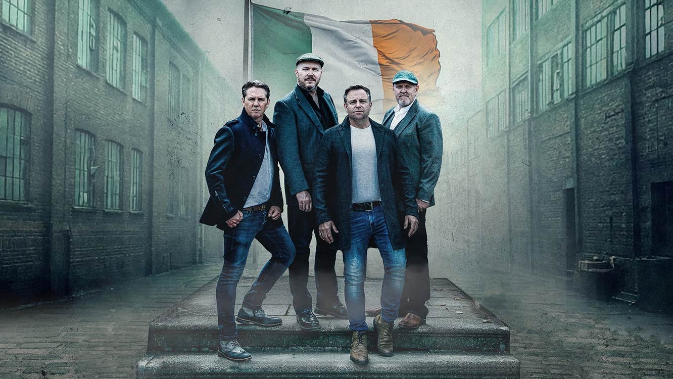 The High Kings - A group of 4 men outside on a couple of steps with old warehouse style buildings either side.
