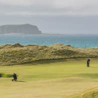 Golfer putting beside the sea at Rospaenna Golf Course, Donegal