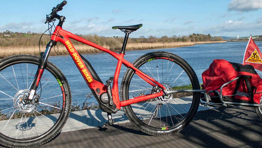 A red bike and child bike trailer parked by the rivershore