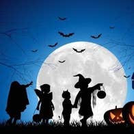 Children trick or treating in the moonlight on Halloween.