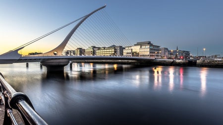 A bridge with the shape of a harp spanning a river in a city