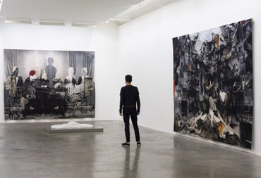 Person viewing two large paintings hanging on white walls in an art gallery room