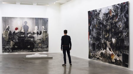 Person viewing two large paintings hanging on white walls in an art gallery room