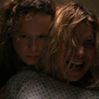 A woman is holding an anguished woman from behind.