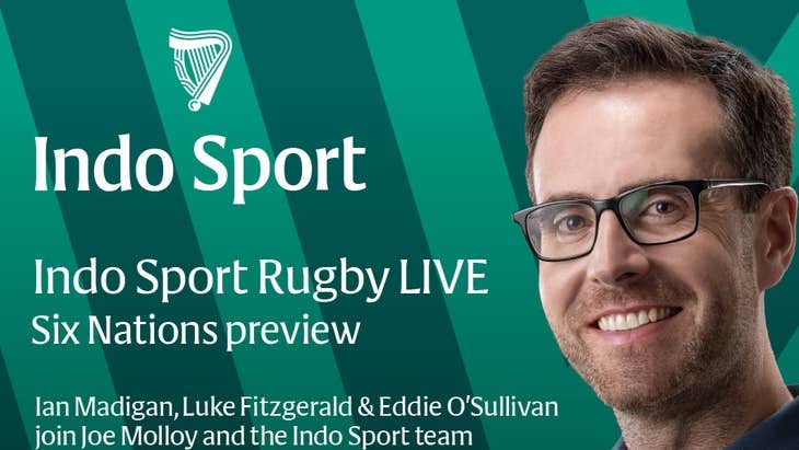 A smiling man in blue shirt with background of green stripes and white text