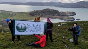 Five hikers holding a solas sign on a hike through hills