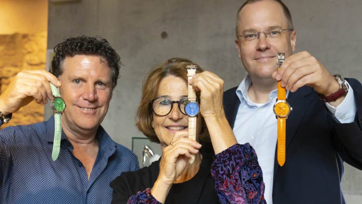 3 smiling adults each holding up a different coloured watch