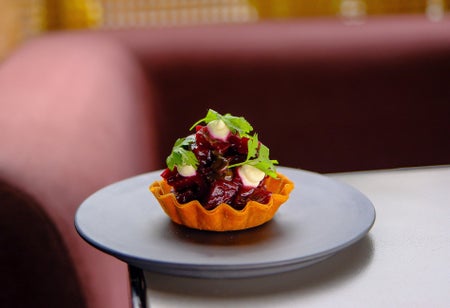 Small filled pastry on a grey plate on a table with red seating behind it