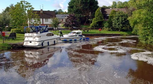 Two boats on the harbour in Ballinamore in County Leitrim near a park