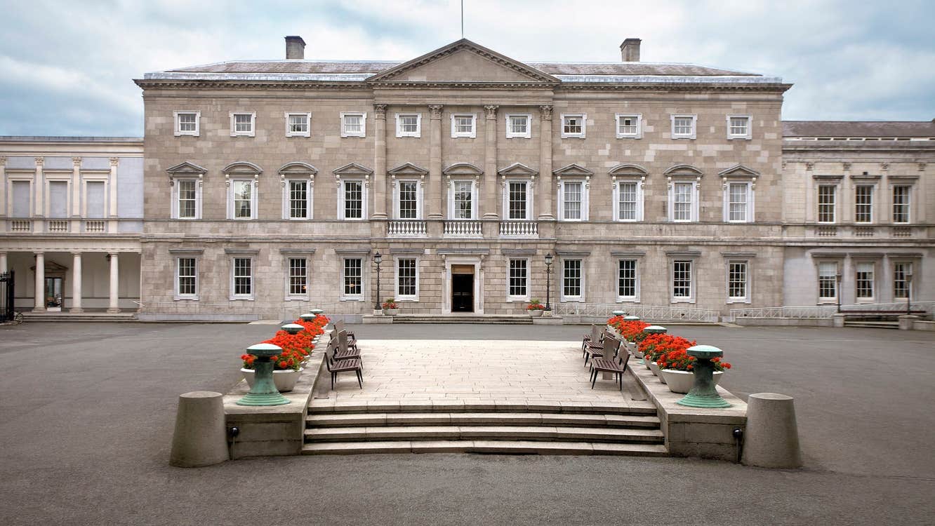 Exterior of a large Georgian mansion with steps lined with flowers in a large courtyard