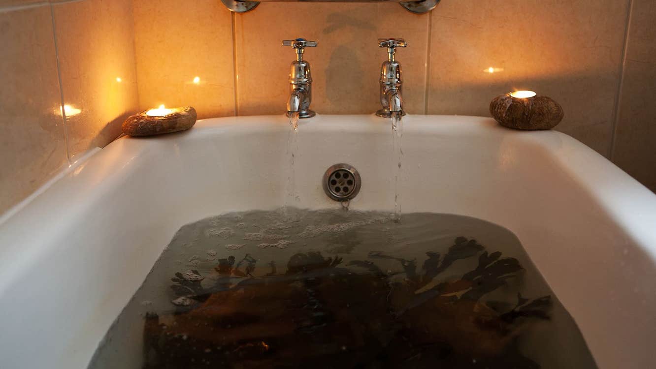 Sea weed soaking in a hot bath of sea water with candles lighting on the bath side