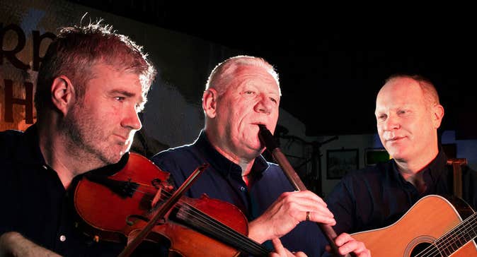 Three musicians playing instruments at the Merry Ploughboy Irish music pub in Dublin