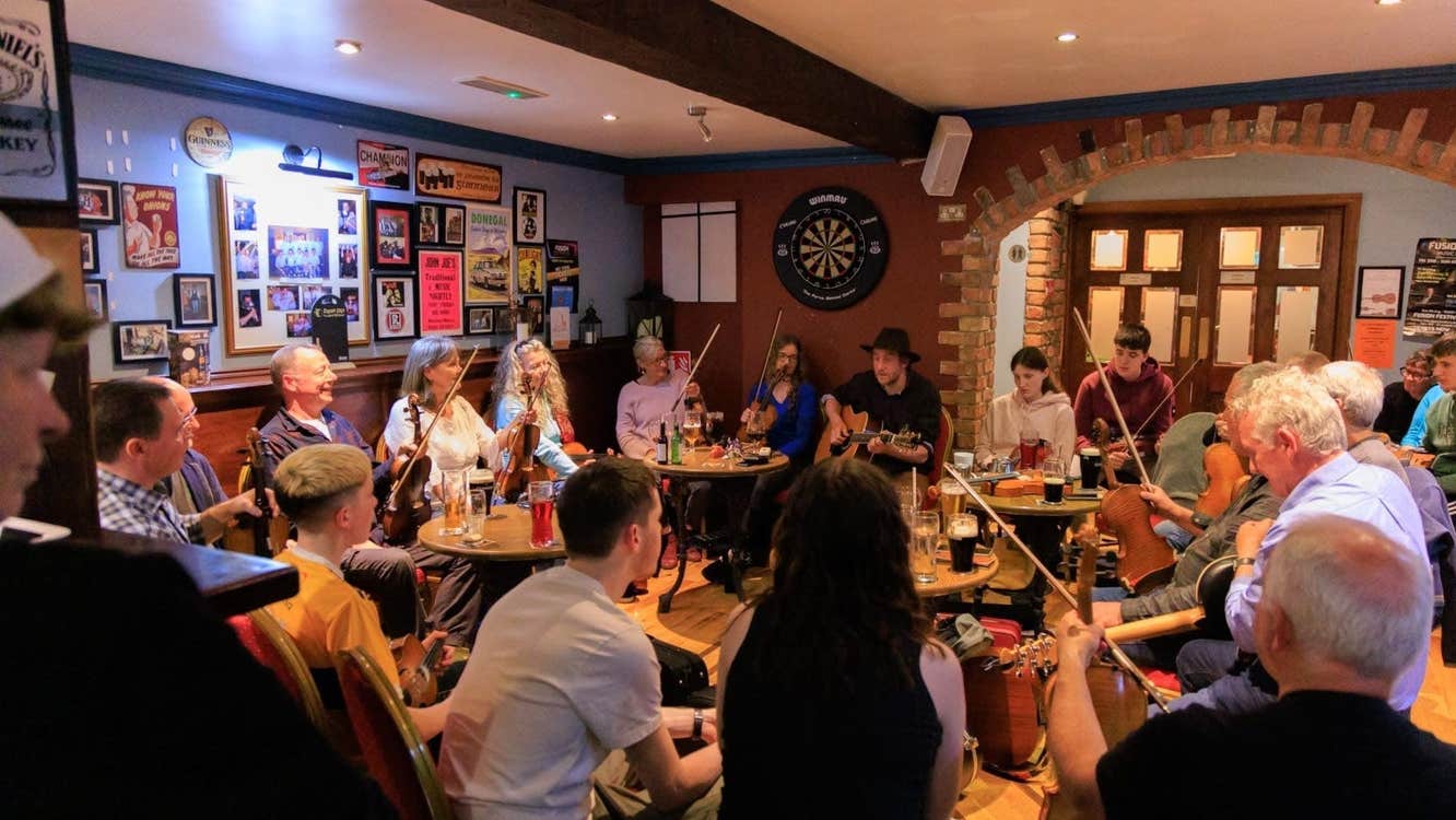 Musicians with instruments sitting around tables in a pub