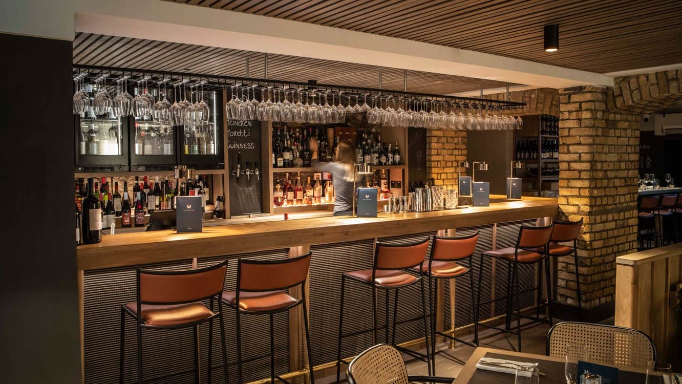 Interior of a bar with a counter six high stools and a table set for service