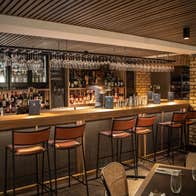 Interior of a bar with a counter six high stools and a table set for service