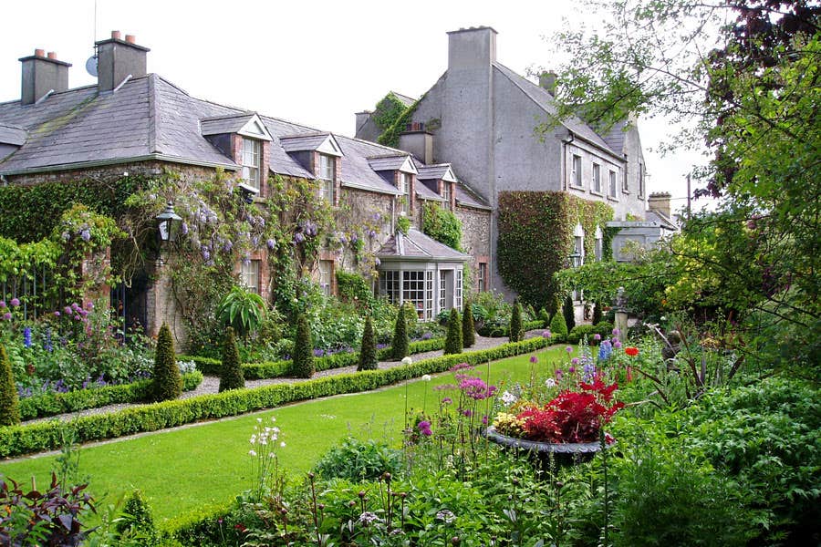 A period house overlooking a garden with lots of shrubs and flowers
