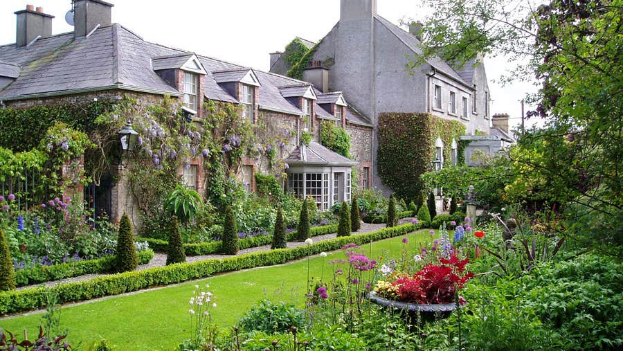 A period house overlooking a garden with lots of shrubs and flowers