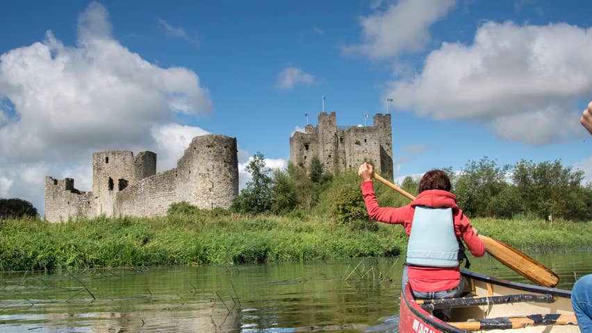Two ladies in a canoe on the River Boyne near castle ruins