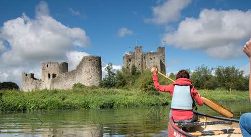 Two ladies in a canoe on the River Boyne near castle ruins