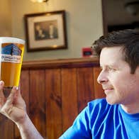 A man holds a pint of Dungarvan Brewery beer up to the light