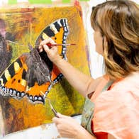 Side view of an artist working on a canvas of a large butterfly